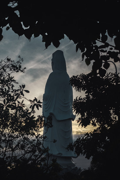 佛像在岘港-越南从背面-日落和云-剪影的树木在前景图片下载