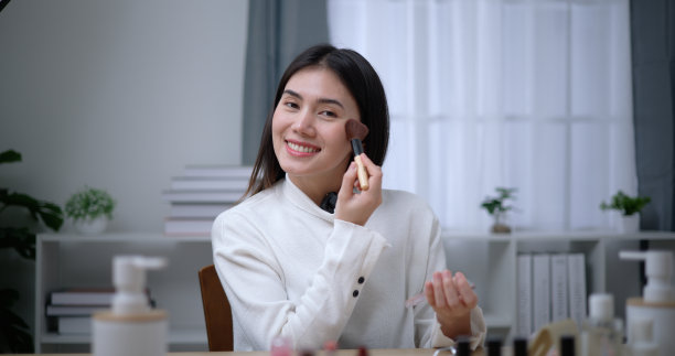 美丽的年轻亚洲女性博主向我们展示了如何化妆和使用化妆品图片下载