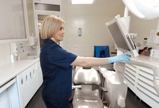 一名中年女牙医在牙科诊所为一天的工作做准备，在接待病人之前打开了监视器图片下载
