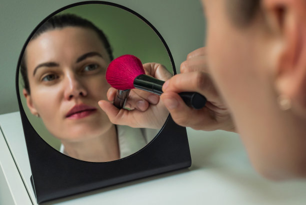 一位欧洲妇女在镜子前化妆。在镜子前化妆。镜子里一个女人的倒影。图片下载