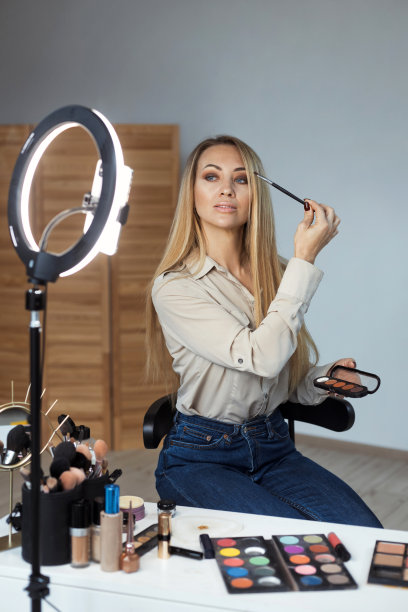 漂亮的年轻女士在网上教化妆，用眼影刷，在工作室里为她的博客录制视频图片下载