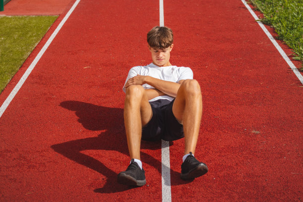 一个有着健壮体格的棕色头发的男孩坐在一个健壮的椭圆形椅子上，用泡沫滚轮按摩他的肌肉，以便更好地恢复。运动后图片下载