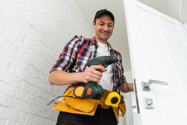 伙计，把门打开。用螺丝刀拧自攻螺钉。不锈钢门铰链在一个白色的门上。图片下载