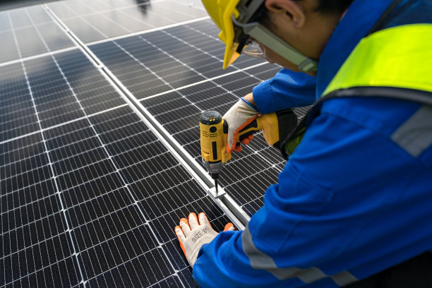 技术人员正在工厂屋顶安装太阳能电池板，亚洲工程师负责监督安装。安装太阳能电池板，将太阳能转化为可持续电力。图片下载