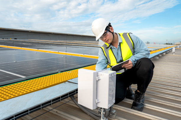 工程师检查安装在工厂屋顶的太阳能板的安装情况，检查太阳能板的安装情况。亚洲工程师将检查数据记录在平板电脑上，监督太阳能电池板的安装。图片下载