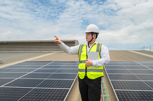 工程师检查安装在工厂屋顶的太阳能板的安装情况，检查太阳能板的安装情况。亚洲工程师将检查数据记录在平板电脑上，监督太阳能电池板的安装。图片下载