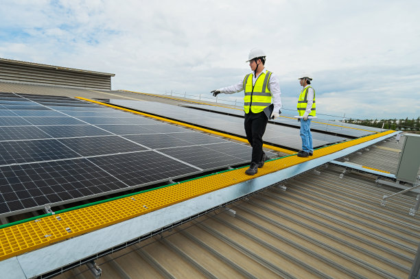工程师检查安装在工厂屋顶的太阳能板的安装情况，检查太阳能板的安装情况。亚洲工程师将检查数据记录在平板电脑上，监督太阳能电池板的安装。图片下载