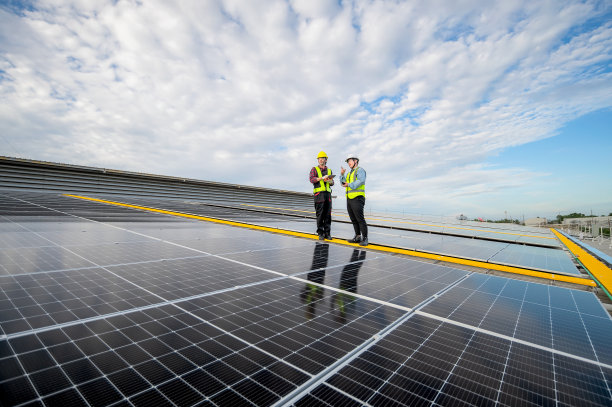 亚洲工程师检查安装在工厂屋顶上的太阳能电池板的安装情况，技术人员、工头在平板电脑上记录检查数据。工程师用无线电通讯指挥、控制工作图片下载