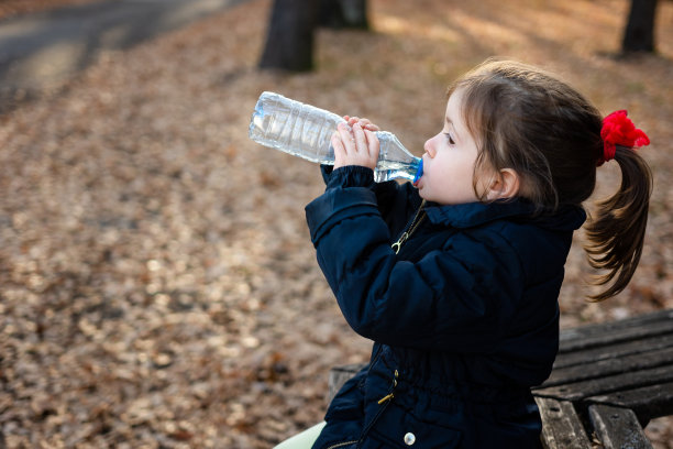 一个女孩在大自然中从瓶子里喝水图片下载