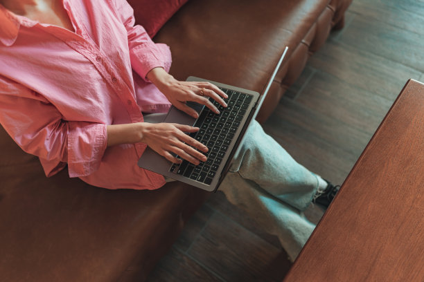 在舒适的联合办公环境中，坐在沙发上用笔记本电脑工作的女性特写图片下载