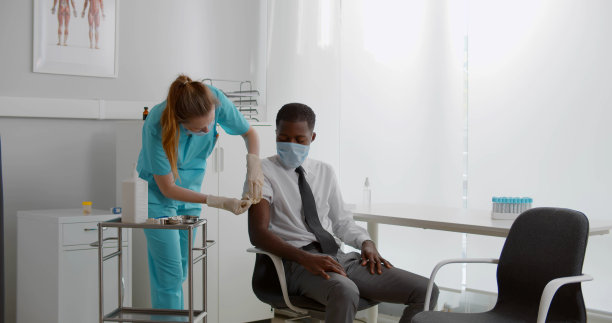 护士戴口罩，用注射器给男性患者注射疫苗图片下载