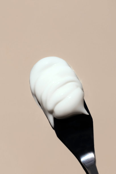 在米色背景上的调色板刀上的化妆品霜的纹理图片下载