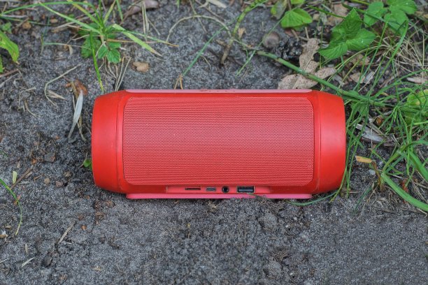 灰色的地上躺着一个红色的移动音乐扬声器图片下载