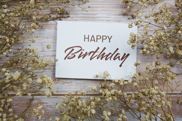 生日快乐的文字在纸卡片与花装饰木制背景图片下载