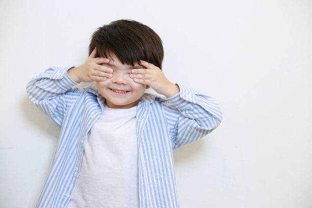 一个小男孩穿着一件很有礼貌的衬衫，用手遮住眼睛，背景是白色的。图片下载