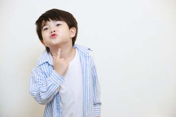 一个小男孩穿着一件礼貌的衬衫，在白色的背景上做着爱的手势和嘴唇图片下载