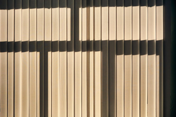 窗户上的垂直百叶窗紧闭，但阳光透过它们，可以看到窗框的轮廓图片下载