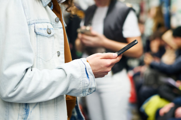 身穿牛仔夹克的年轻人用手机发短信的特写图片下载