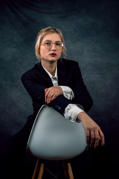 时尚美女模特的肖像，穿着经典的西装白衬衫，在椅子上摆姿势图片下载