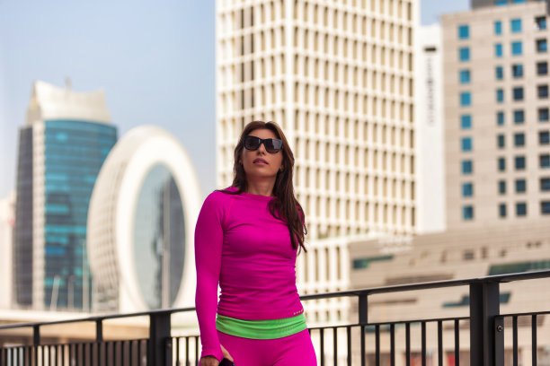 穿着运动服、戴着太阳镜的运动女士在迪拜城市堤坝背景下的肖像。在城市环境中锻炼的时尚女性，户外锻炼。健康生活方式概念。广告文案空间图片下载