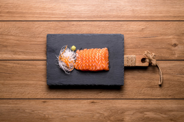 三文鱼生鱼片被放在一个黑石盘上图片下载