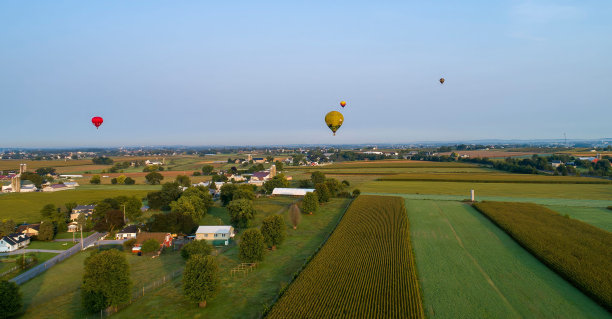 白天，热气球在农场和村庄上空飞行图片下载