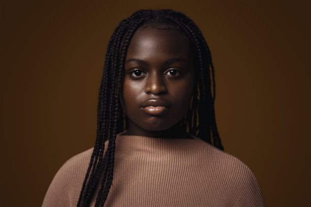 一个严肃的少年在深棕色背景下的肖像图片下载