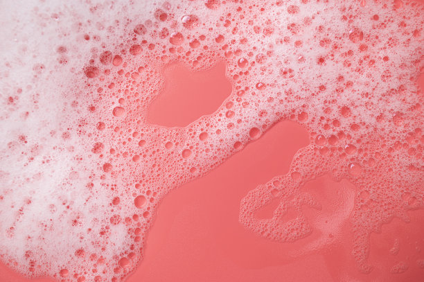 纹理白色泡沫与泡沫在粉红色的背景。用于洗涤、卫生、洗发水、肥皂、沐浴啫喱、摩丝的化妆品泡沫。极简主义的化妆品和医疗背景平铺图片下载