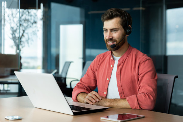 快乐的客服人员带着视频通话耳机和笔记本电脑，微笑着在线咨询客户帮助下订单。图片下载