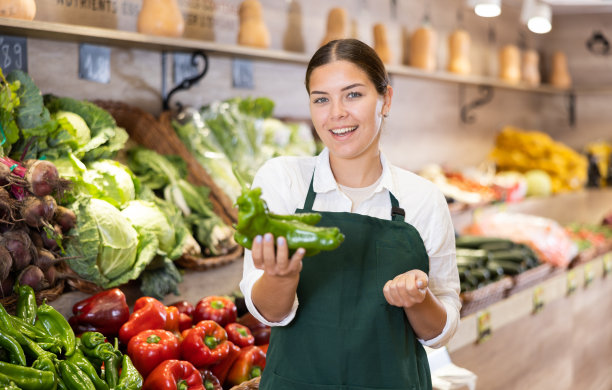 快乐的年轻女售货员在杂货店展示辣椒图片下载