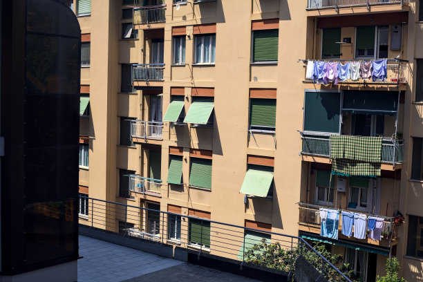 在一个阳光明媚的日子里，意大利小镇上，一幢带有阳台和晾衣绳的公寓外立面图片下载