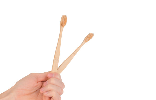 白色背景下，男性手里拿着两把木制牙刷图片下载