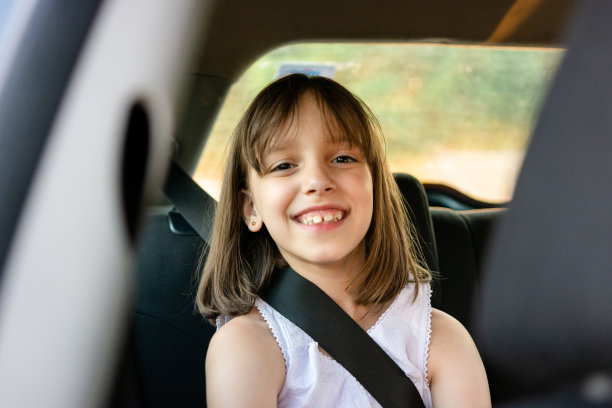 微笑的小女孩坐在汽车座椅上看着镜头图片下载