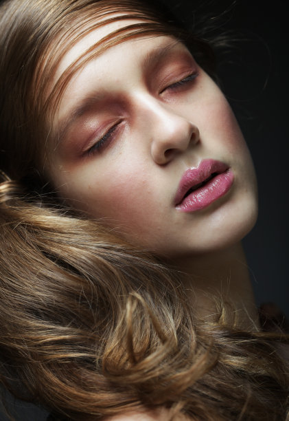 美丽的女人与化妆在粉红色的色调。年轻的女性模型与辫子在黑色的背景。图片下载