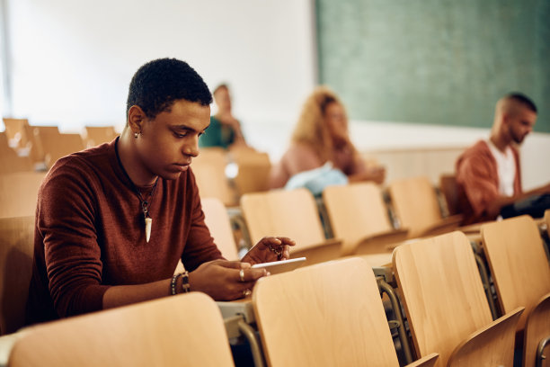 一名黑人学生在大学听讲座时用触控板进行电子学习。图片下载