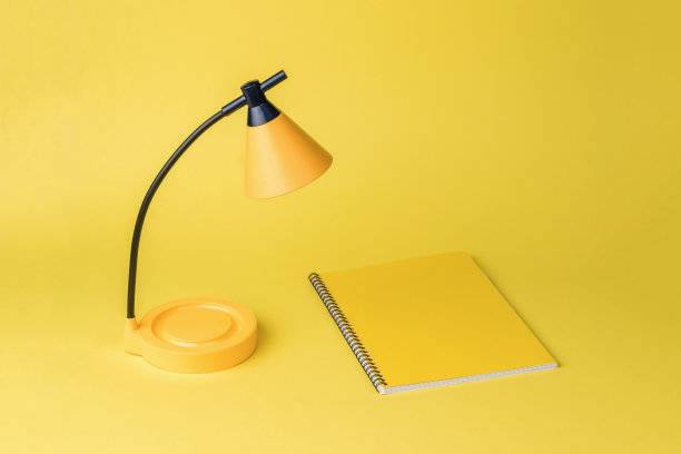 最小的概念。黄色的台灯，黄色的笔记本，黄色的背景。图片下载