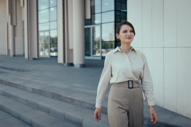 身着商务装的年轻白人女性走出办公楼去吃午饭图片下载