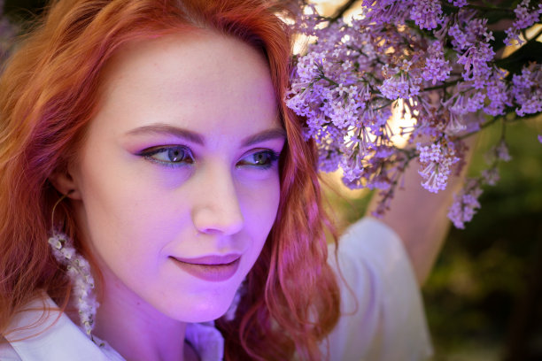 快乐的女孩在公园散步。照片在丁香花的背景。特写肖像。都市景观中的成年女孩，开朗的典范。图片下载