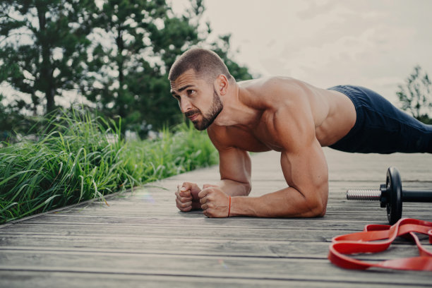 肌肉健美者在平板支撑姿势中展示耐力，强壮的二头肌，通过户外运动锻炼保持良好的身体形状。集中俯卧撑。图片下载