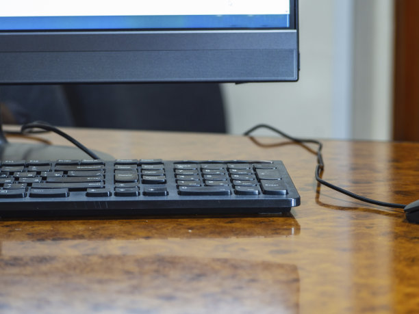 个人电脑:工作场所在办公室。一个黑色的显示器，键盘和电脑鼠标放在办公室的桌子上图片下载