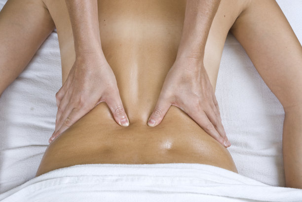 双手在白色亚麻布上进行背部按摩图片下载