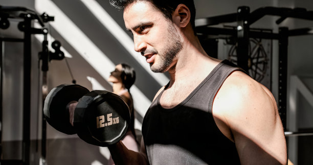强壮的运动员在健身房用哑铃锻炼图片下载