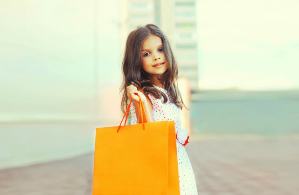 小女孩的肖像与购物袋在城市街道图片下载