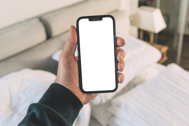 在酒店卧室的游客拿着带有空白屏幕的智能手机进行预订和预订应用程序图片下载