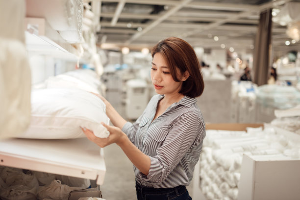 一位亚洲女性正在商场挑选枕头。图片下载