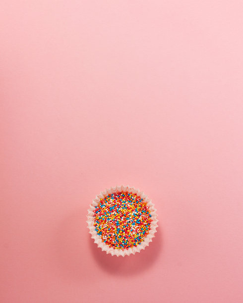 纸杯蛋糕衬垫底部从上往下涂了彩色糖。平铺俯视图。糖果烹饪概念在亮粉色的纸背景全国烹饪日图片下载