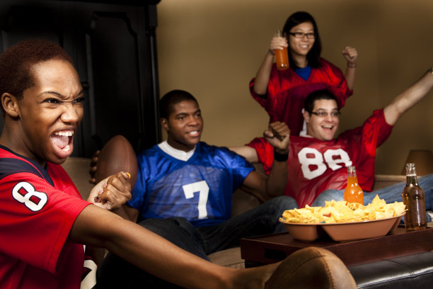 足球迷在家里看电视比赛。欢呼。图片下载