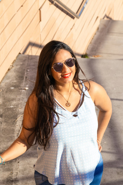 年轻的拉丁孕妇在公园的楼梯上微笑图片下载