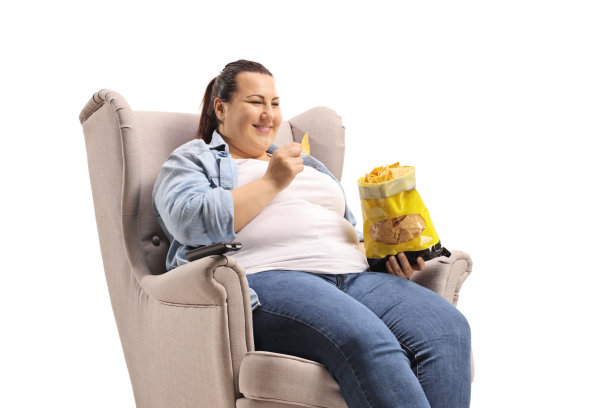 胖乎乎的女人坐在扶手椅上吃着玉米片图片下载