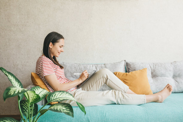 一位年轻漂亮的欧洲女子用笔记本电脑在家远程工作、社交、网上购物、创造图片下载